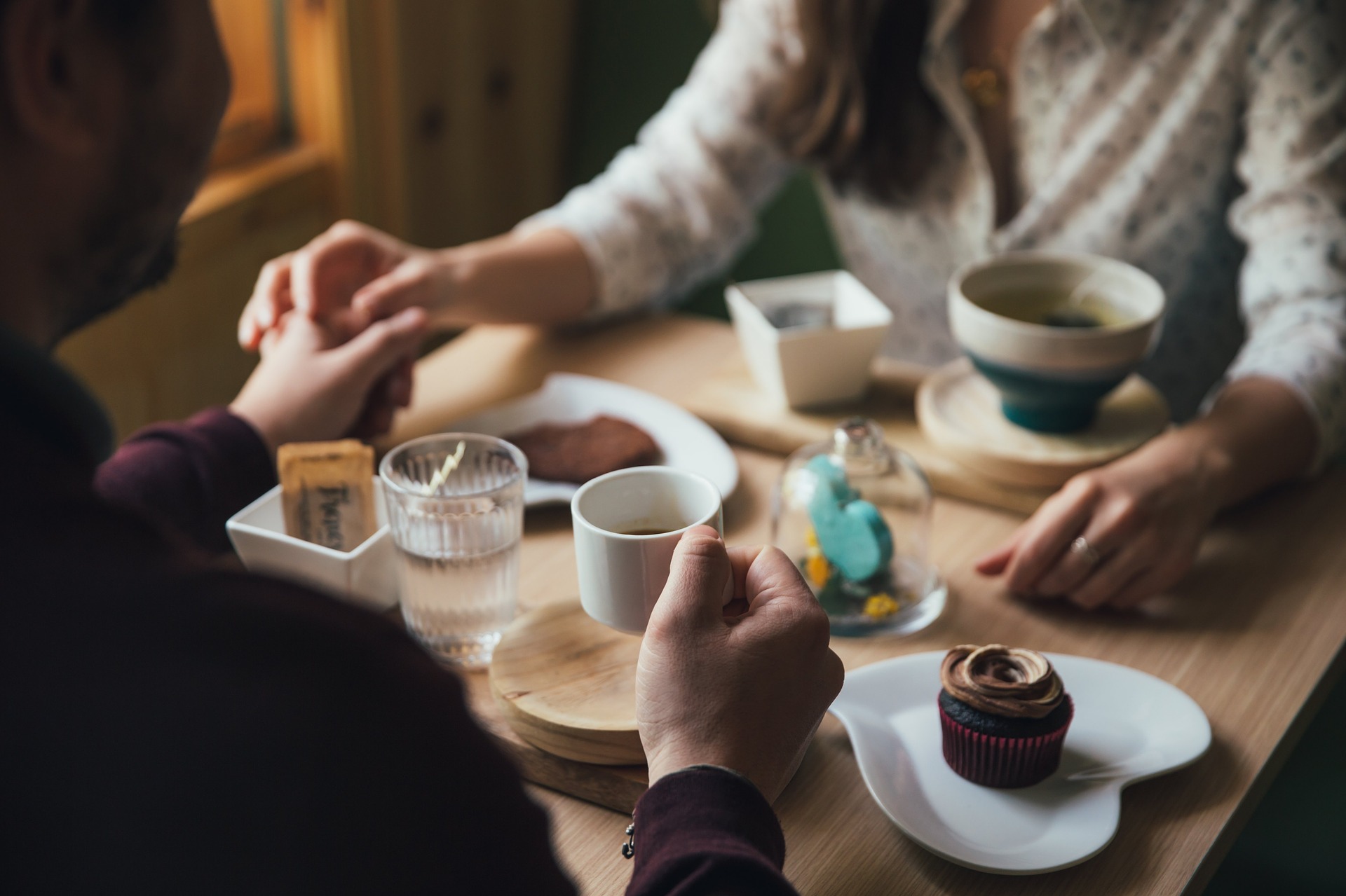 Couple holding hands over coffee and dessert - How to go out for the night and leaving your pet