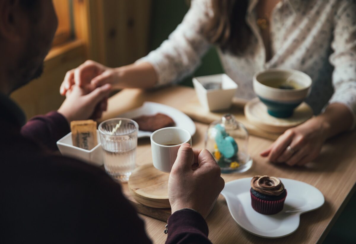 Couple holding hands over coffee and dessert - How to go out for the night and leaving your pet